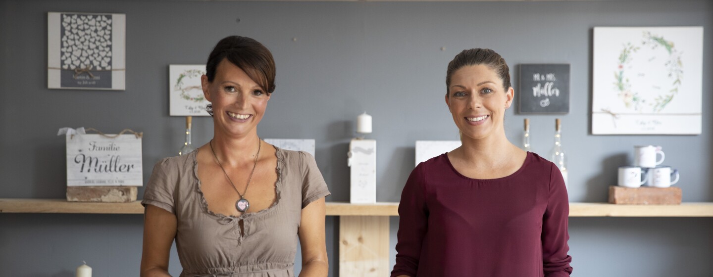 Yivi und Anja von Manufaktur Liebevoll stehen in ihrem Laden und lächeln in die Kamera.
