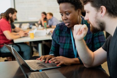 A woman and a man work on laptop computers.