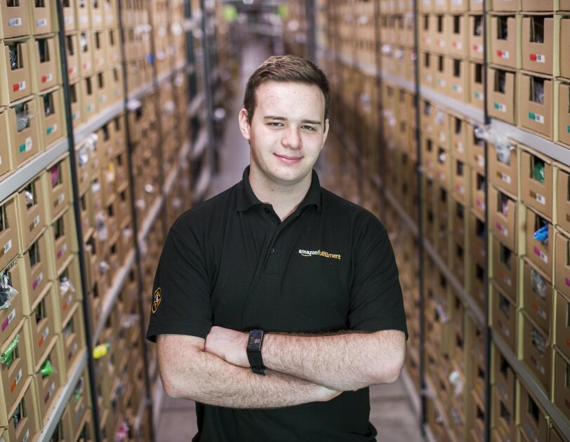 Jonathon Williams stood in Amazon Fulfilment Centre with arms crossed