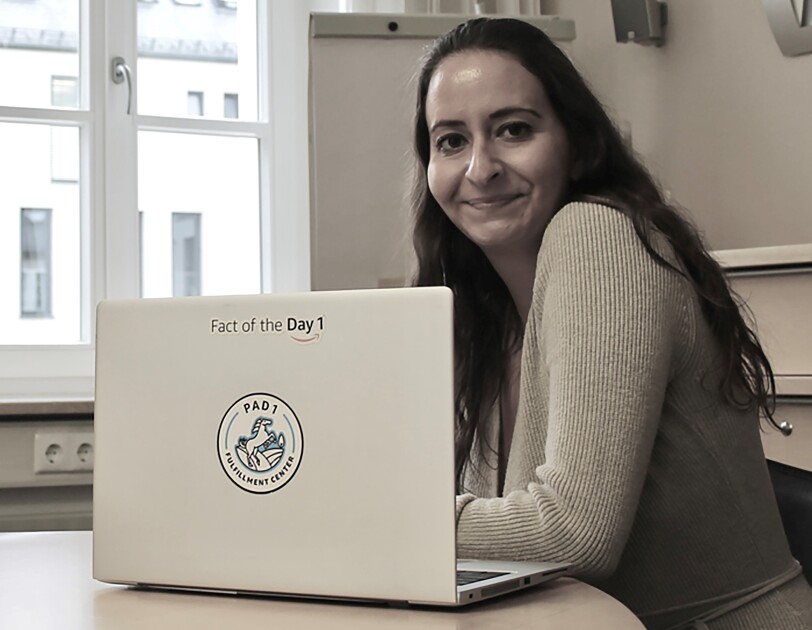 Eine junge Frau mit langen dunklen Haaren vor einem Laptop