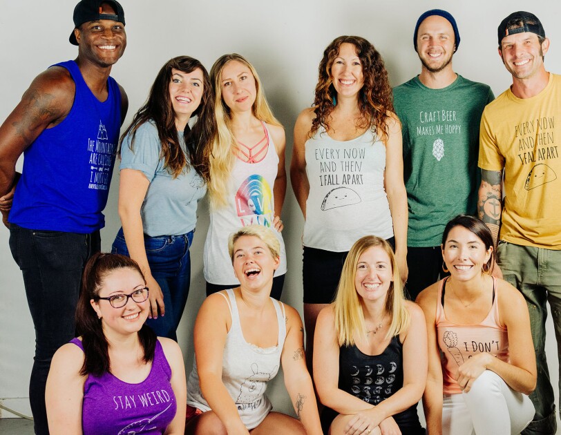 Ten young adults gather together for a posed photograph, smiling at the camera.