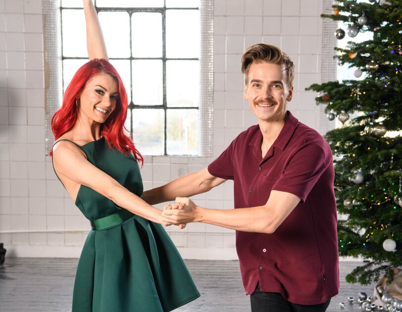 Dianne Buswell and Joe Sugg dancing in a studio, behind them is a Christmas tree.
