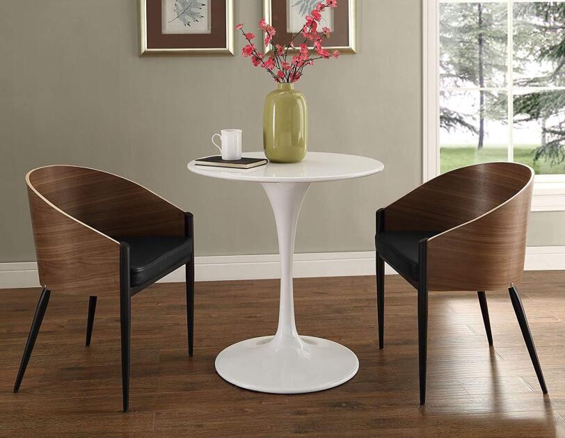 Two Philippe Starck-style wood chairs with pin legs sit on either side of a white lacquer pedestal table.