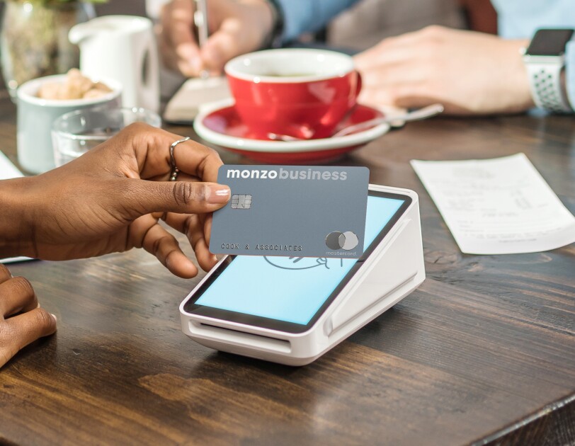 Persons hand with Monzo business card over pay machine