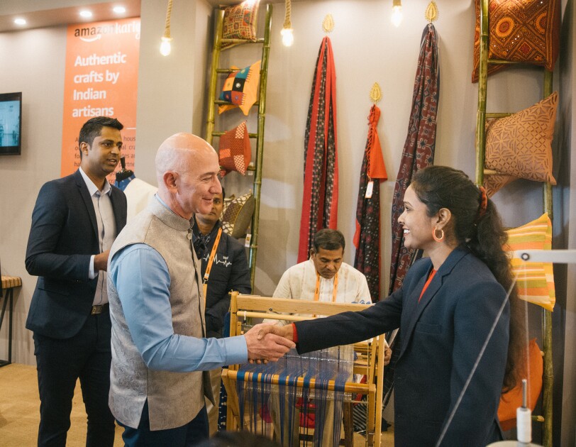 Jeff Bezos shakes the hand of a woman artisan and small business owner.