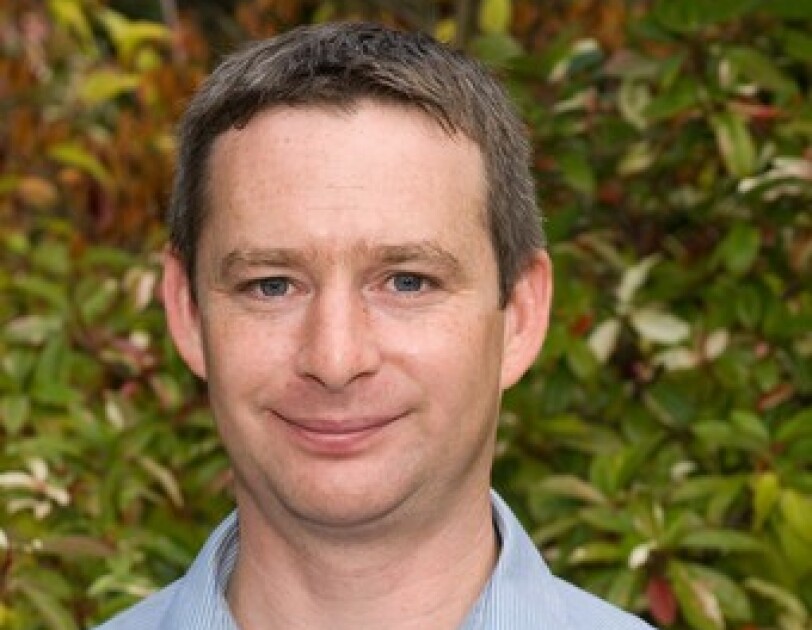 Richard Kneller dressed in a blue shirt looking directly at the camera
