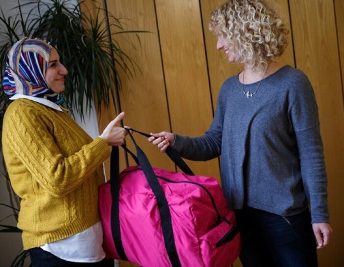 Eine Mutte bekommt eine Baby Bag überreicht. Sie freut sich über die Untersützung.