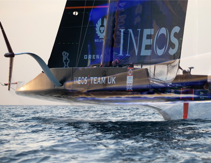 A close up image of the INEOS Team UK, AC75 challenger boat hovering above water level.