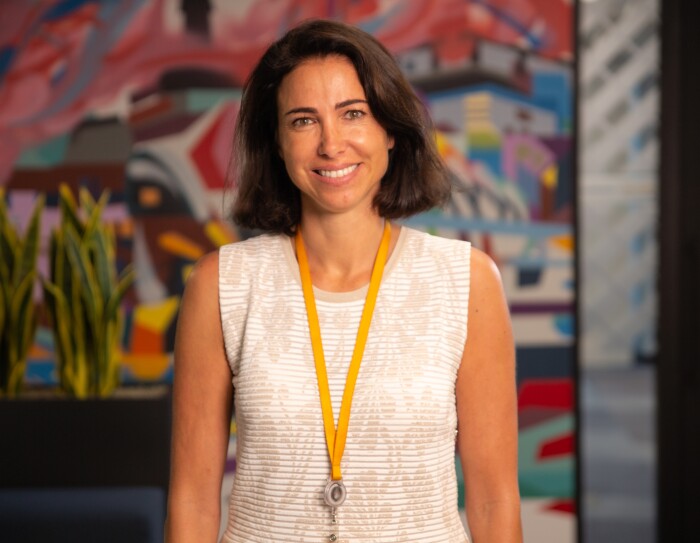 Ruth Díaz, Vicepresidenta de Amazon Fashion en Europa. En las oficinas corporativas de Amazon en Madrid, Ruth aparece en un plano hasta la cintura. Llev amedia melena morena, un jersey blanco con dibujos de flores en beis. Lleva la tarjeta de Amazon en una cadena amarilla de ropa. Con los ojos azules, mira a cámara con una sonrisa.