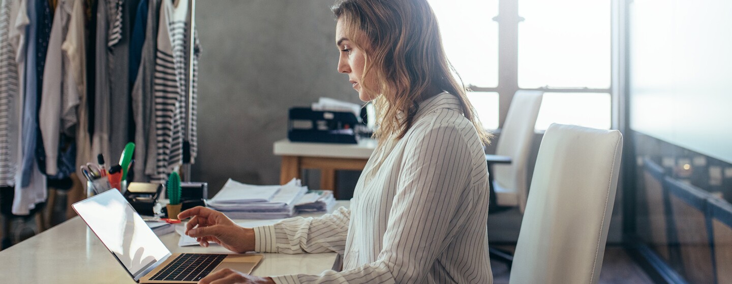 A woman works at a notebook computer, in a small business setting.