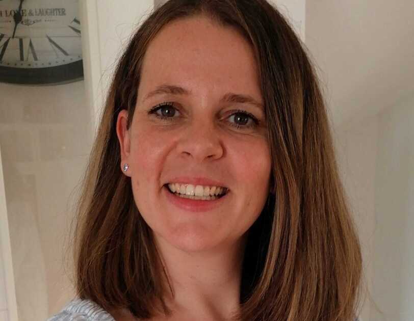 Eine Frau mit kurzen blonden Haaren lacht in der Kamera.