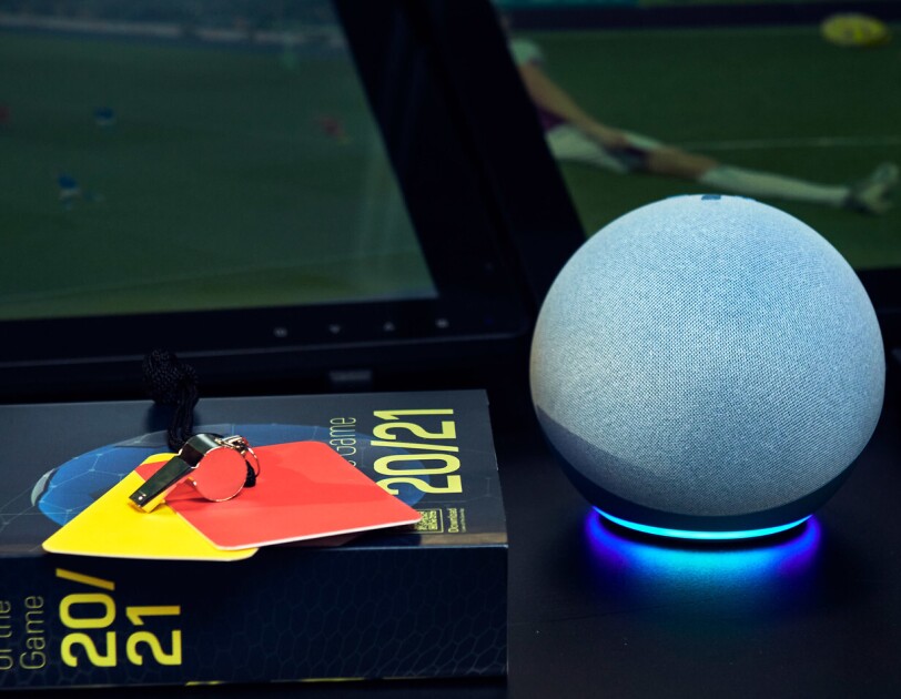 The Echo Dot on a table with a book of football rules and a red and yellow card