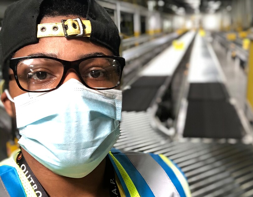 Close-up of a man wearing a protective mask in a large workspace.