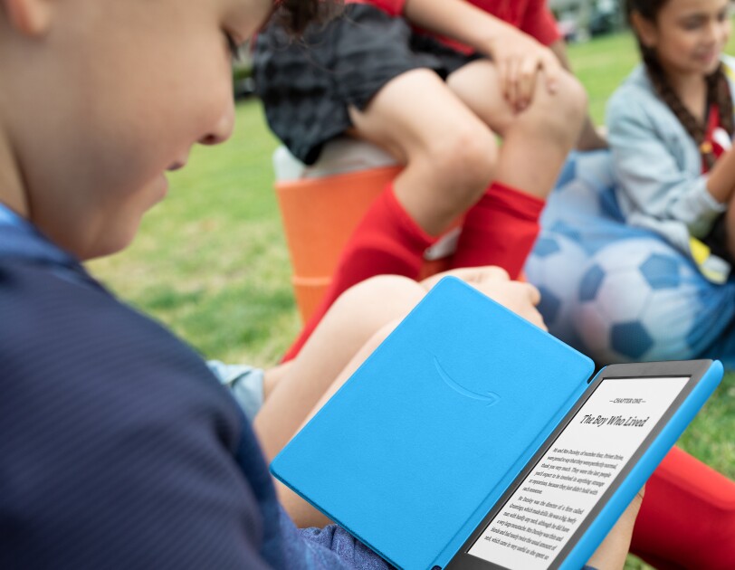 Child reading a book at the park on the Amazon Kindle Kids Edition
