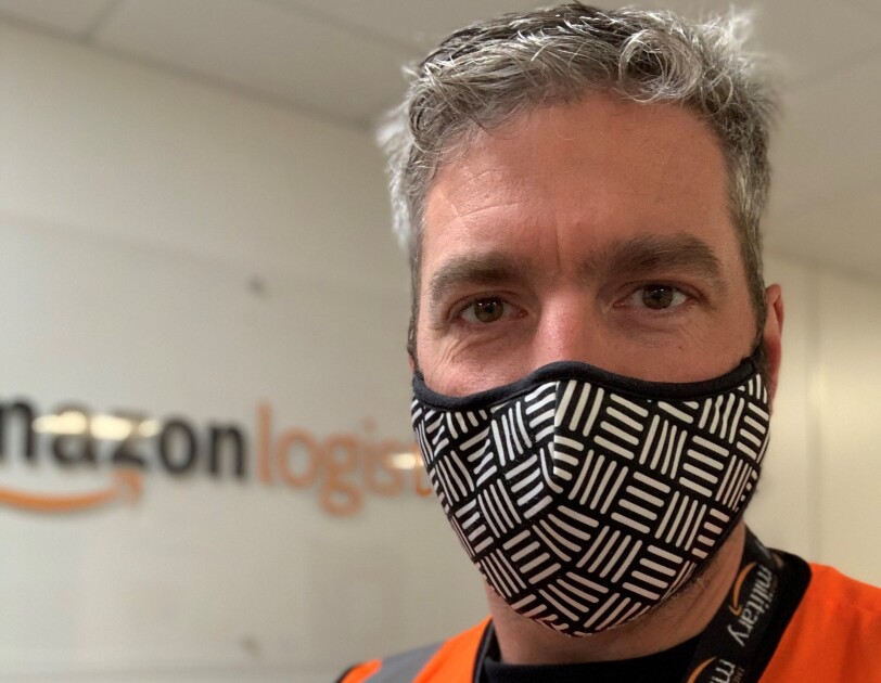 Amazon employee wearing a mask and orange high vis vest