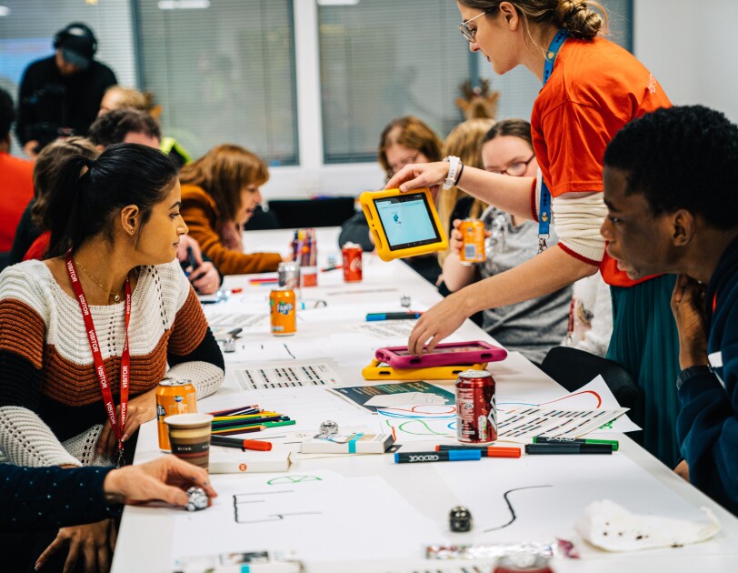 Row of children from Barnardo's doing arts and crafts at robotics workshop. They are also being handed tablet computers.