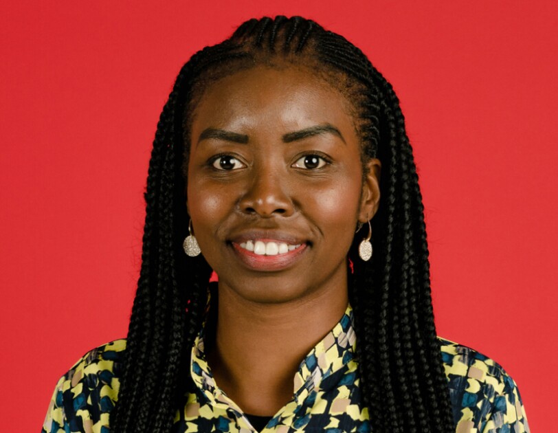 Headshot of Ramat Tejani in front of a bright red background.