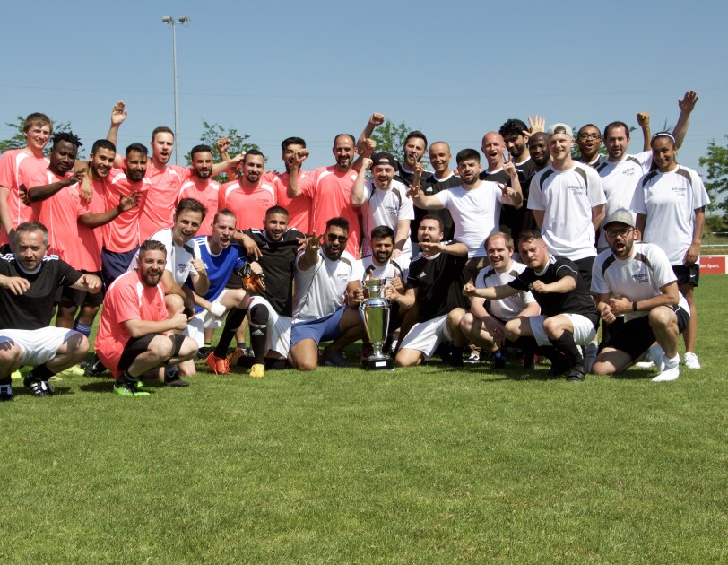 Verschiedene Fußballer in roten, schwarzen und weißen Trikos. Sarmi ist ganz rechts im Bild zu sehen. Sie ist die einzige weibliche Spielerin.