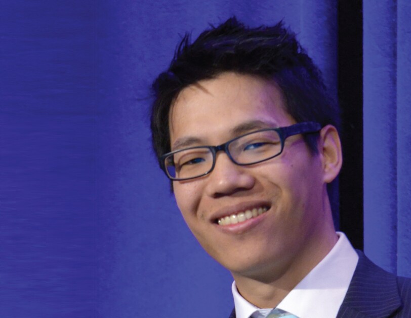 Headshot of William Lau in front of a blue curtain.