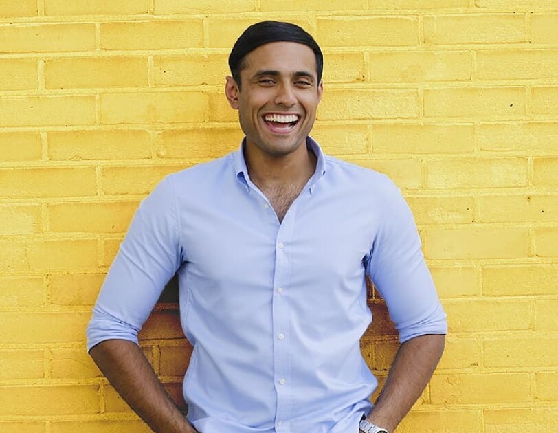 Dhruvin Patel, Founder of Ocushield, standing in front of a yellow brick wall.
