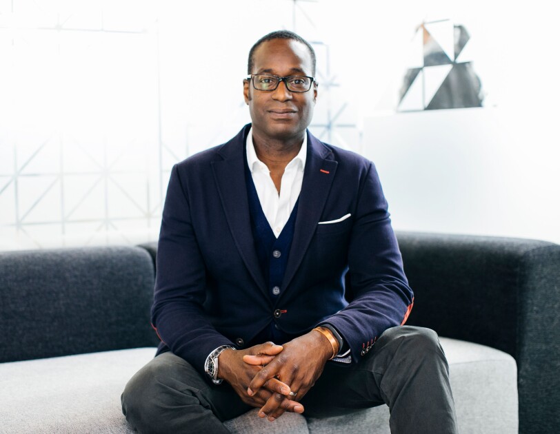 Oz Alashe dressed in a smart suit and sat on a sofa