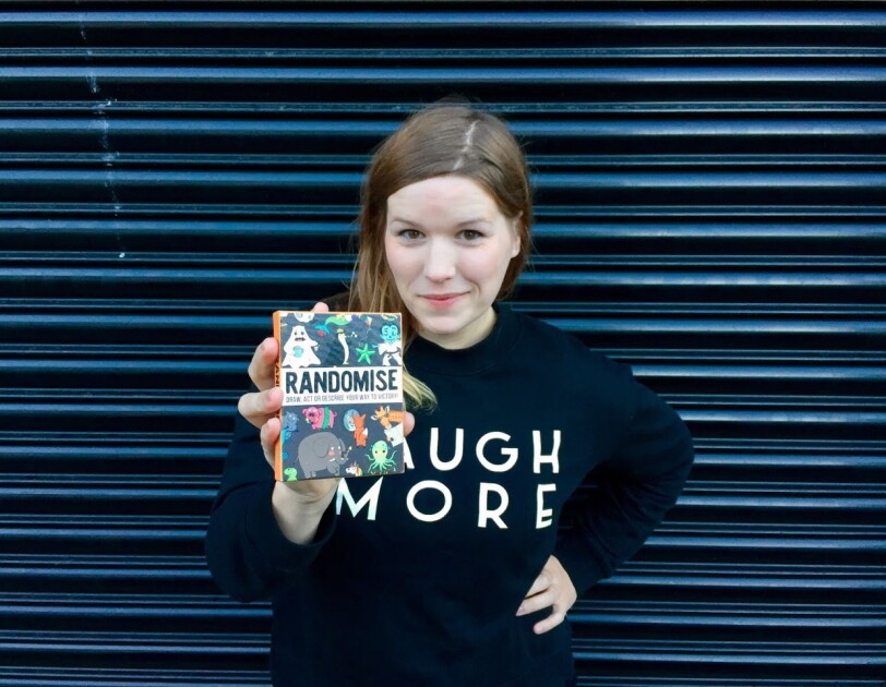 Gamely Games - Hazel holding up Randomise game to camera