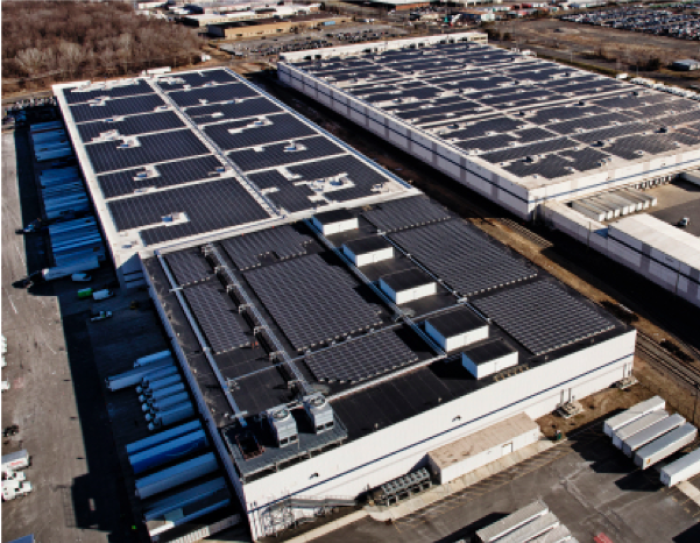 Aerial view of of two Amazon fulfilment facilities with solar systems on their rooftops.