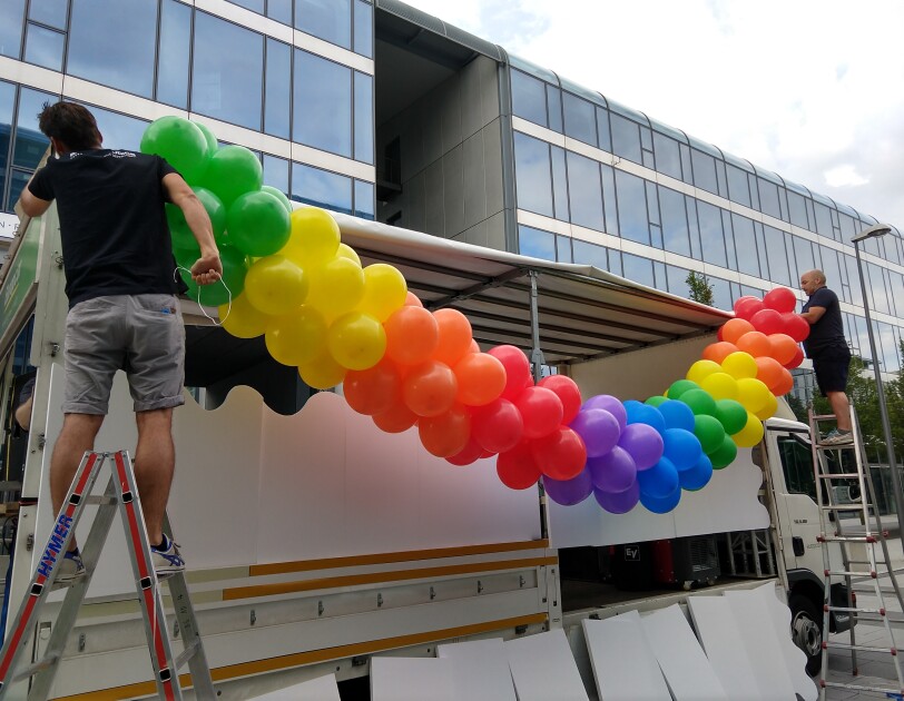Zwei Männer stehen auf Leitern und befestigen Luftballons am Glamazon-Wagen.