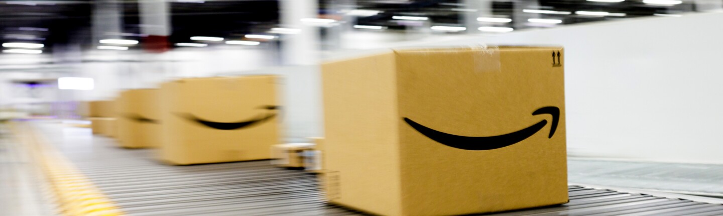 Amazon smile boxes move move along a conveyor belt within an Amazon Fulfilment Center or warehouse.