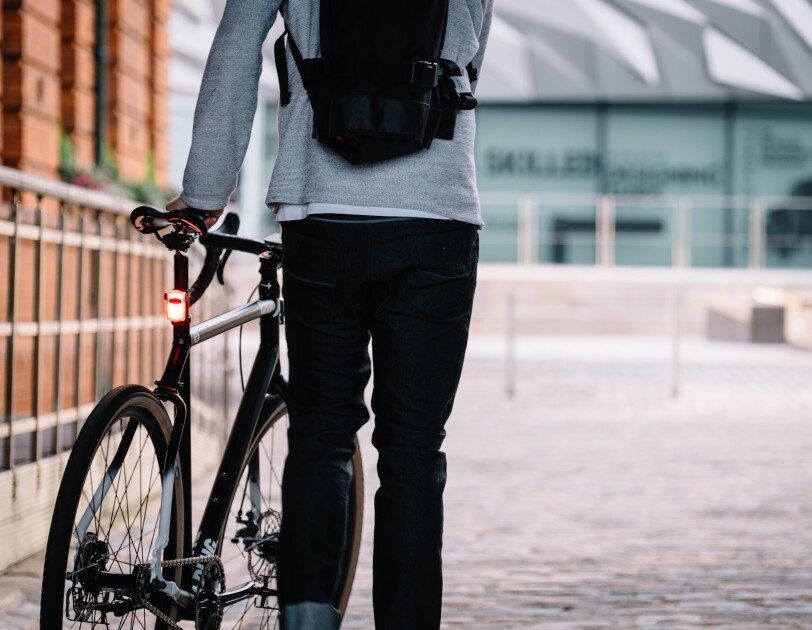 Cyclist stood with his back to camera holding a bike