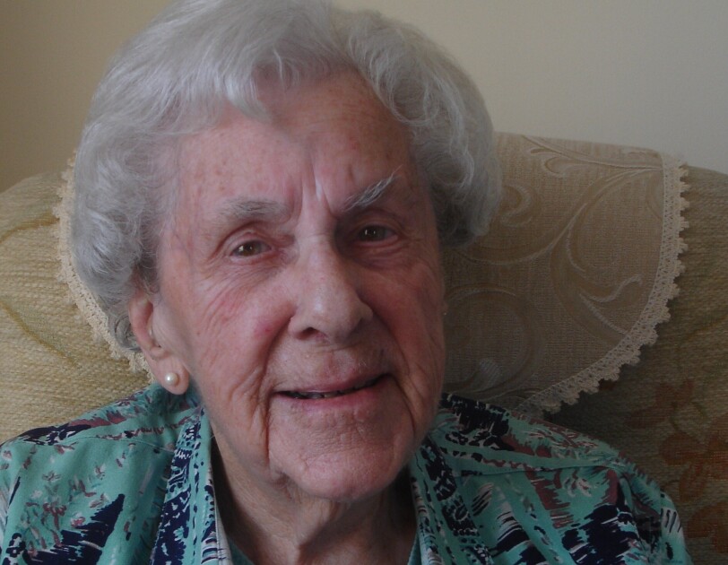 lady with grey hair wearing a blue top and looking straight at the camera