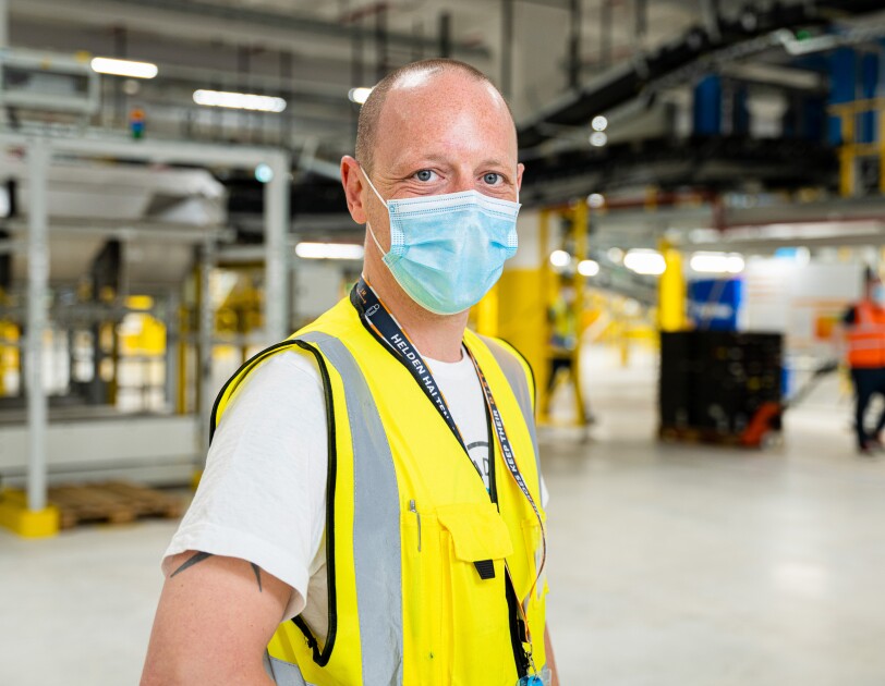 Marcel Flügel mit Maske und Weste im Amazon Logistikzentrum in Oelde