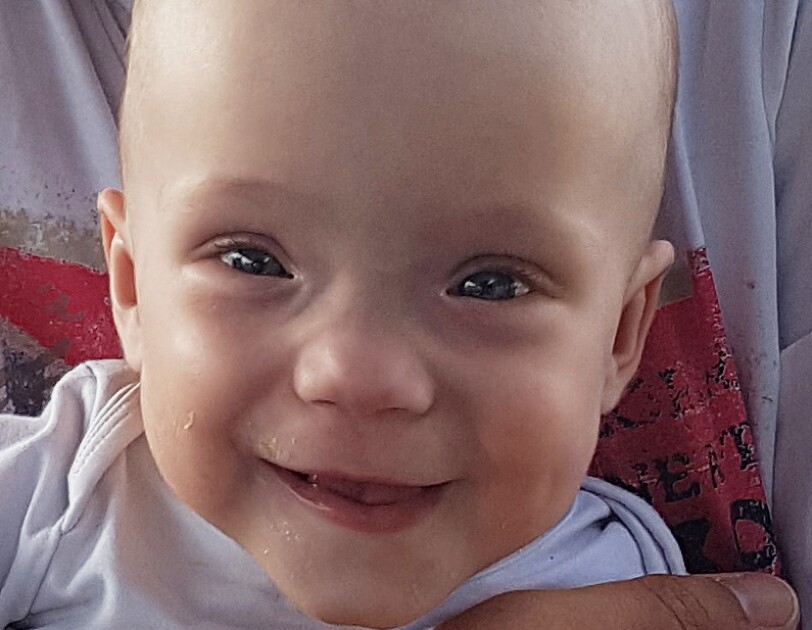 Lena ist ein kleines Baby. Sie hat große Augen und lacht in die Kamera.