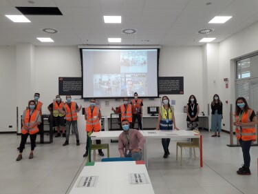 Operatori di magazzino posano in un'area comune del centro di distribuzione Amazon di Vercelli. Indossano la mascherina, sono distanziati.