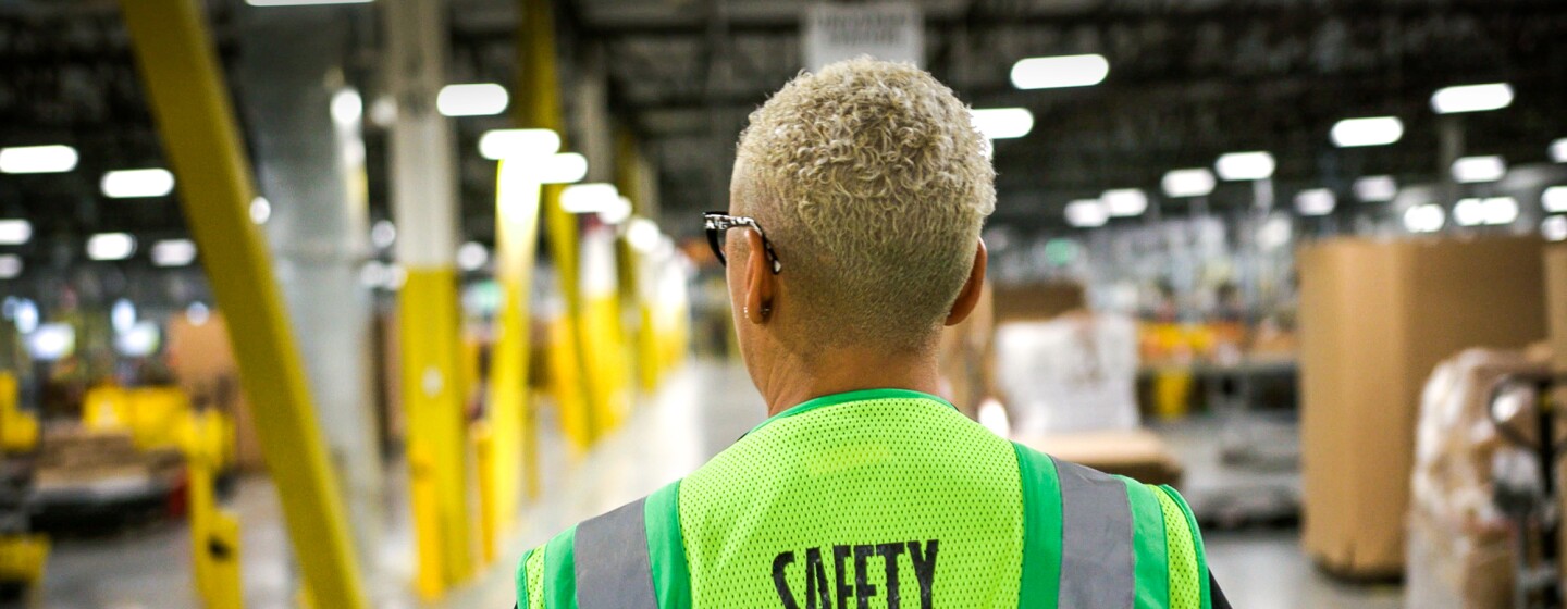 A person wearing a safety vest in a warehouse.