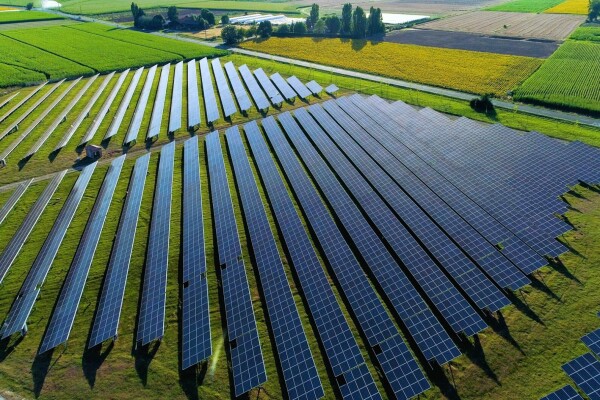 An image of a field of solar panels with lush, green fields in the background