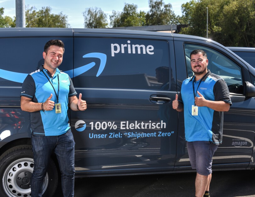 2 junge Männer in blauen Amazon Shirts vor einem Prime Lieferfahrzeug.