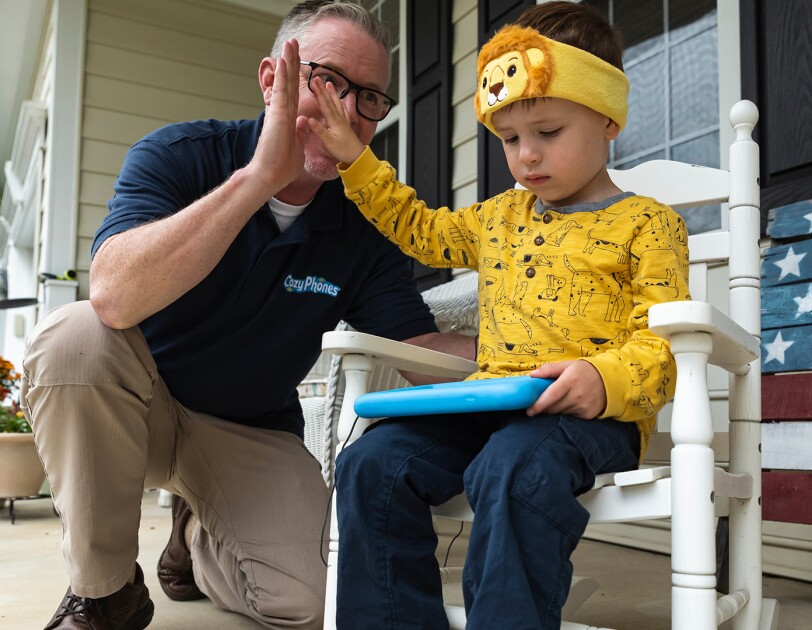 A man gives a high-five to a child sitting in a rocking chair.