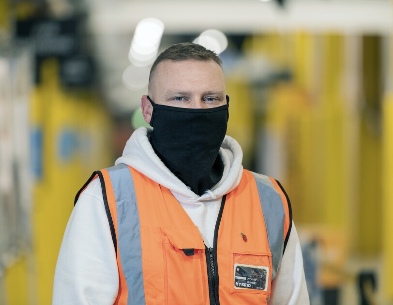 Marcin Jeznach wearing a mask and high-vis jacket in an Amazon Fulfilment Centre.