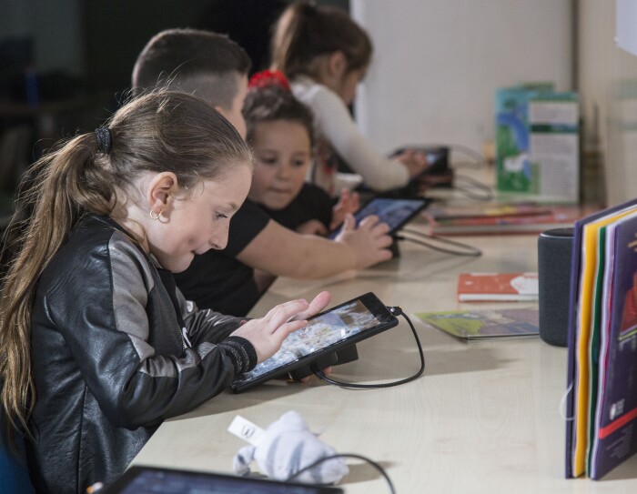 Bambini giocano con i tablet Fire messi a disposizione da Amazon per la sala multimediale della Biblioteca di Scampia