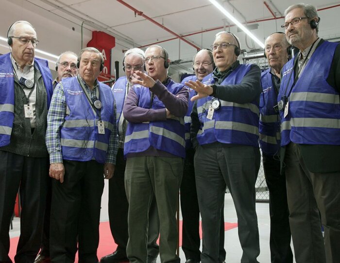 Un grupo de ingenieros jubilados durante una visita al centro logístico. Todos ellos visten con chaleco azul.