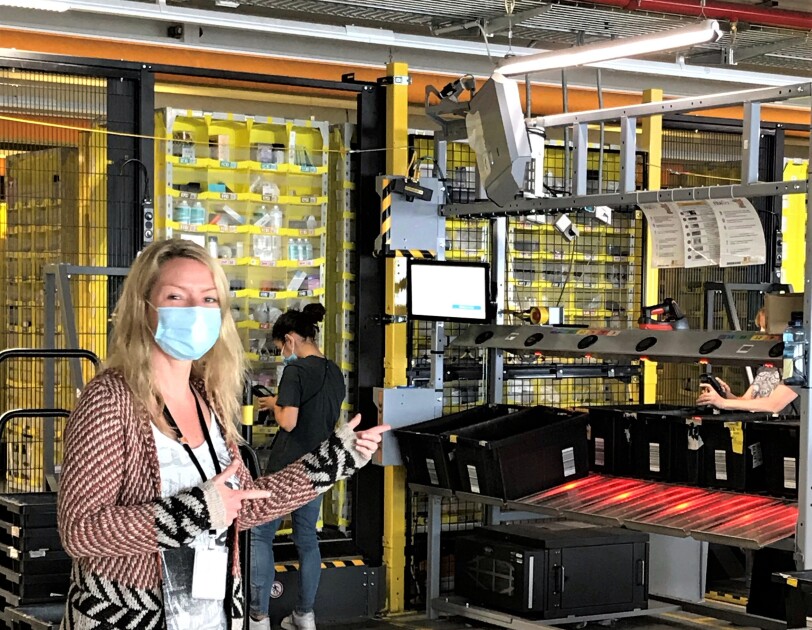 Eine blonde Frau mit Mundschutz in einer Lagerhalle