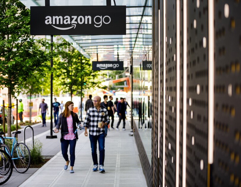 A man and a woman walk in front of the Amazon Go store in Seattle, WA.