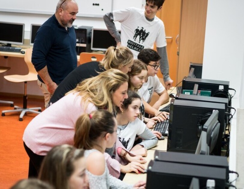 Mädchen und Jungen sitzen vor Computer-Bildschirmen. Sie schauen alle in die Bildschirme.
