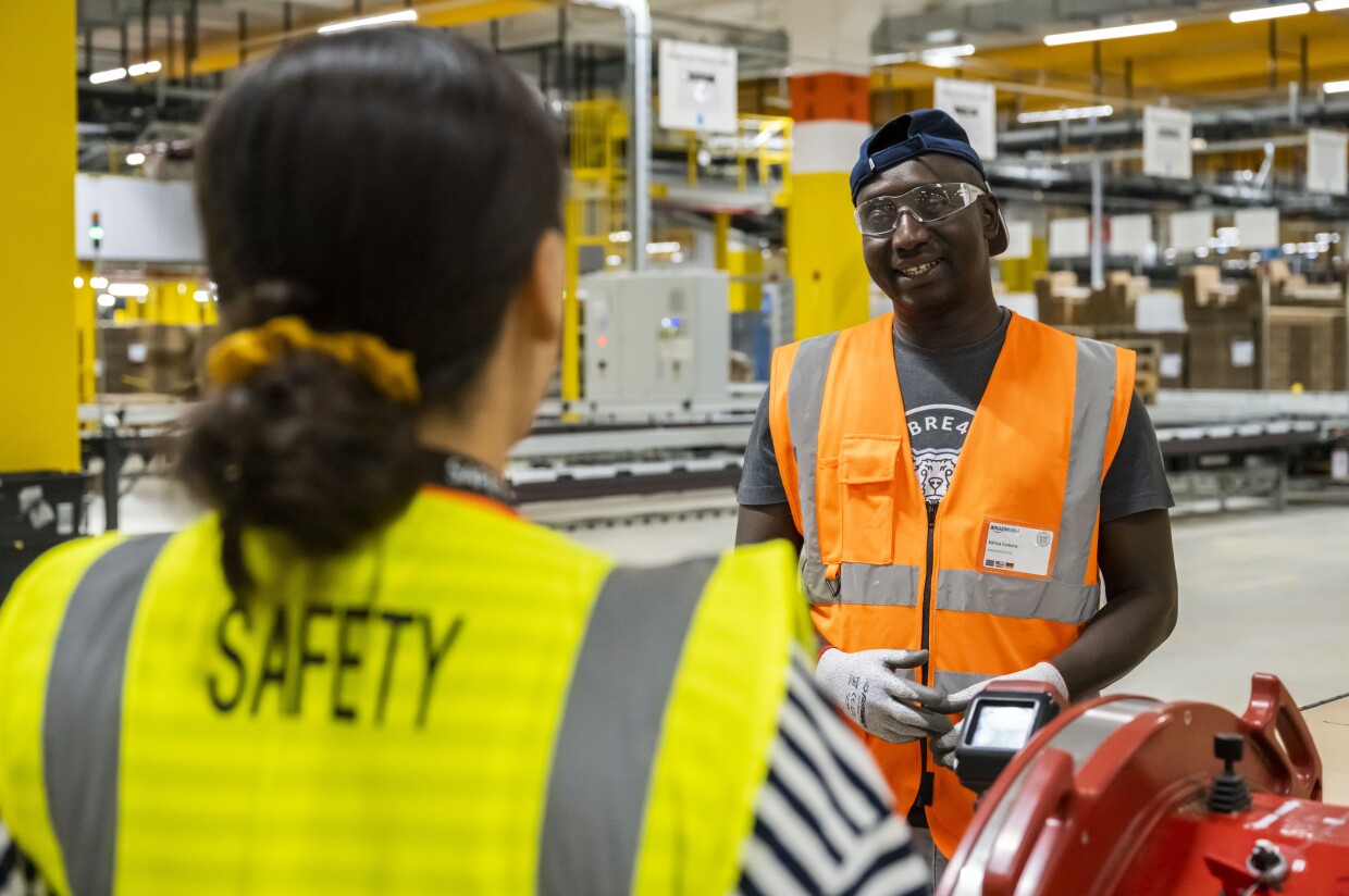 Eine Amazon Safety Mitarbeiterin im Gespräch mit einem Kollegen.