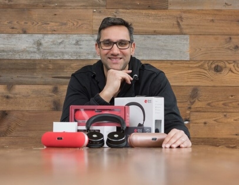Zamir Cajee, Founder of iQualTech, sitting at a table with his products on front of him.