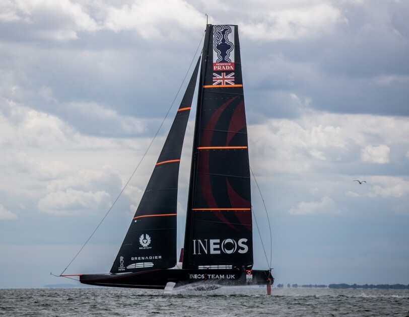 An image of the AC75 challenger boat being tested out on the water. The boat has the INEOS Team UK branding on it.