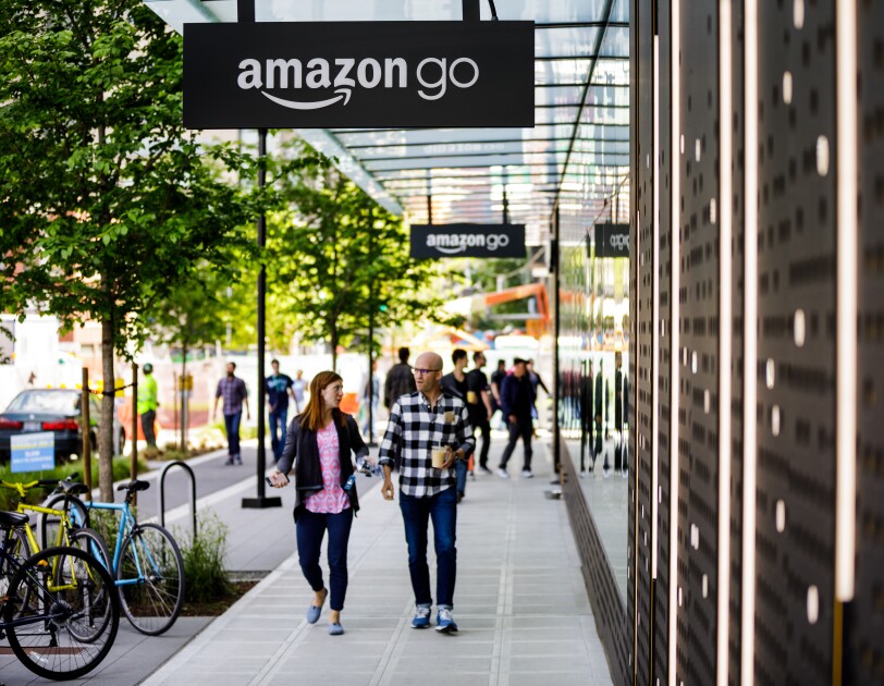 A man and a woman walk in front of the Amazon Go store in Seattle, WA.