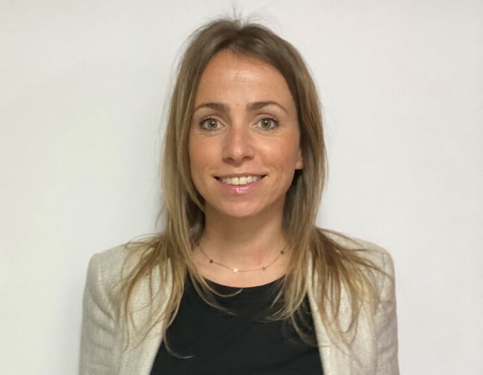 Ana Cruz Dorado, responsable de Recursos Humanos en SVQ1 (centro logístico de Amazon Robotics en Sevilla). Con una jersey negro y una americana gris. Se aprecian unos jeans. El pelo rubio por el hombro y los ojos verdes. Lleva una cadena de oro con estrellas.