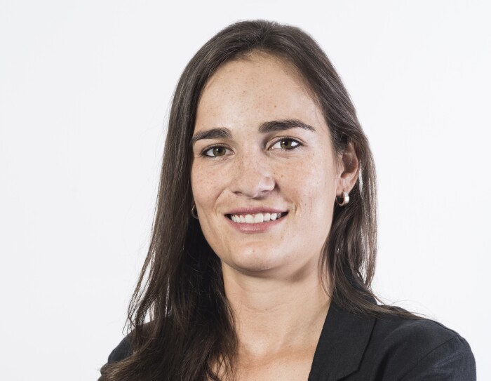 Eugenia. Pelo largo castaño liso, pendientes, sonriendo a la cámara y con los ojos también castaños.